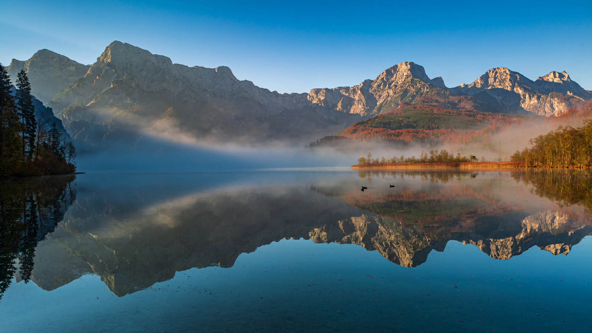 Bergsee mit klarer Spiegelung der Drei Zinnen unter blauem Himmel – Sinnbild für innere Klarheit und das Gesetz der Spiegelung